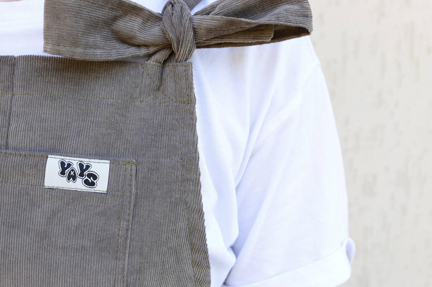 female model posing in YAYS Mink Grey, front view, extra close-up, front pocket, logo tag and strap bow, detail showing