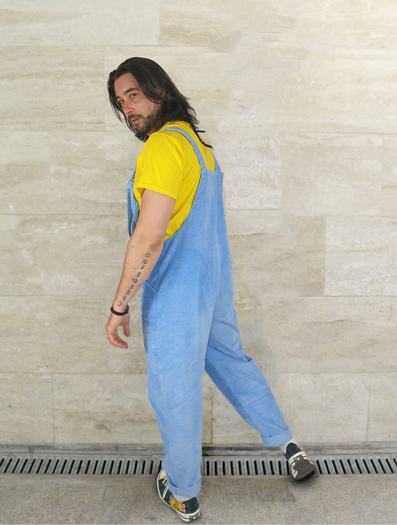 Male model posing in YAYS corduroy unisex dungarees in Serenity Blue, back side view