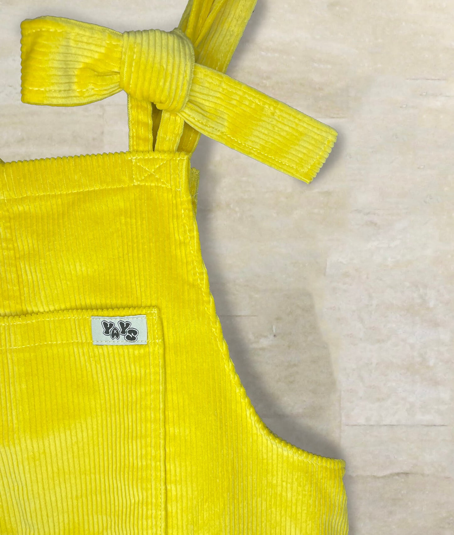 Yays corduroy cotton unisex dungarees close-up, front pocket, logo and bow strap details showing