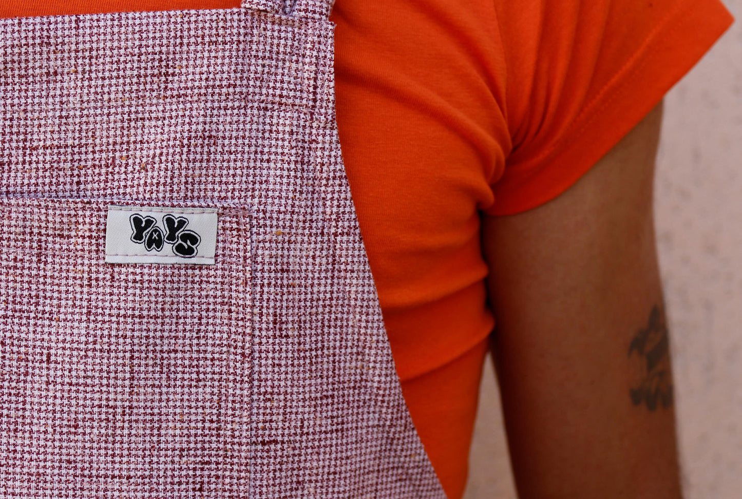 man wearing YAYS linen overalls, close-up shoowing front pocket and YAYS logo details